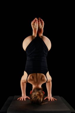 Siyah üzerine izole edilmiş yoga amuda kalkma egzersizi yapan vücutlu bir kızın arka görüntüsü. 