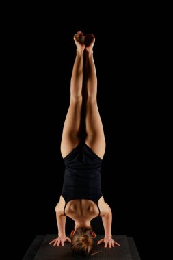 Siyah üzerine izole edilmiş yoga amuda kalkma egzersizi yapan kadın. 