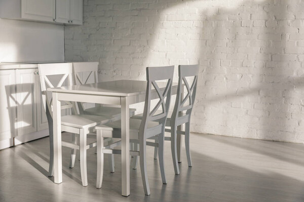 sunlight near chairs near table in modern kitchen 