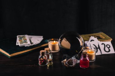 KYIV, UKRAINE - JANUARY 9, 2020: selective focus of tarot cards and crystal ball with occult objects on wooden and black background clipart