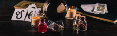 KYIV, UKRAINE - JANUARY 9, 2020: selective focus of crystal ball with occult objects on wooden background, panoramic shot clipart