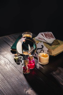 KYIV, UKRAINE - JANUARY 9, 2020: selective focus of crystal ball, candles and occult objects on wooden and black background clipart
