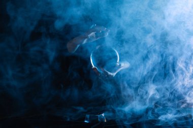 Koyu mavi üzerinde duman olan kristal küreyi tutan cadının kırpılmış görüntüsü 