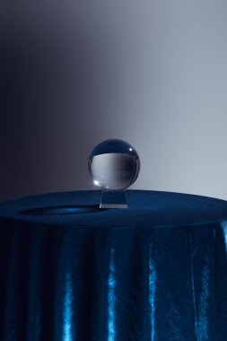 Yuvarlak masada kristal top ve gri üzerinde koyu mavi masa örtüsü. 