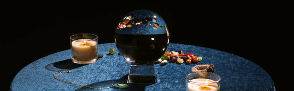 Crystal ball, candle and fortune telling stones on dark blue velour cloth, panoramic shot