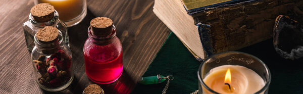 Jars with herbs and tincture, books and candles on wooden background, panoramic shot