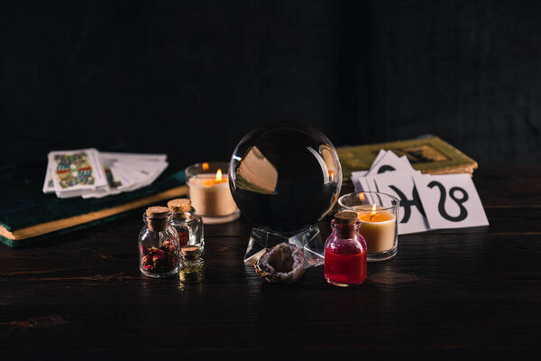 KYIV, UKRAINE - JANUARY 9, 2020: selective focus of crystal ball, books and occult objects on wooden and black background