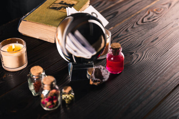 Выборочный фокус хрустального шара с книжными и оккультными предметами на деревянном фоне
