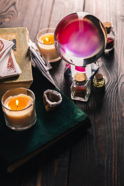 KYIV, UKRAINE - JANUARY 9, 2020: selective focus of crystal ball, books, candles and occult objects on wooden background
