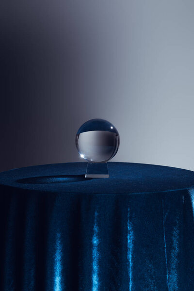Crystal ball on round table with dark blue tablecloth on grey 