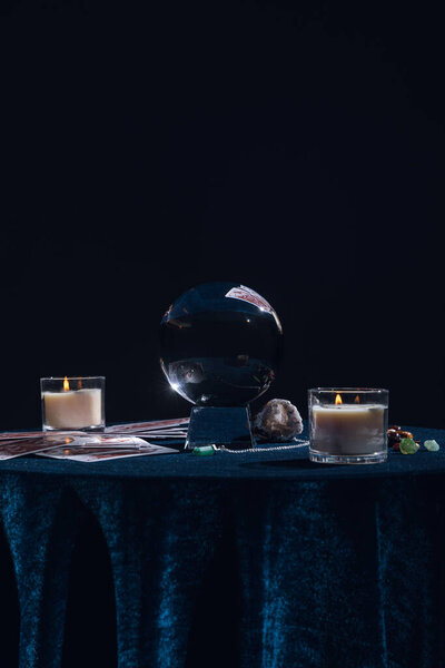 КИЕВ, УКРАИНА - 9 ЯНВАРЯ 2020: Хрустальный шар с оккультными предметами на круглом столе изолирован на черном
