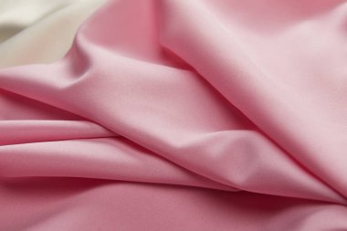 Saten pembe ve beyaz yumuşak ve dalgalı kumaşın yakın görüntüsü