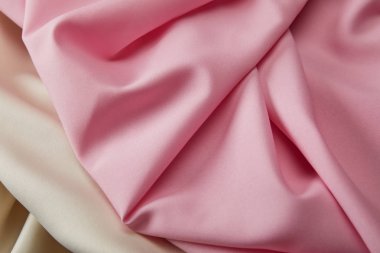 Saten pembe ve beyaz yumuşak ve dalgalı kumaşın yakın görüntüsü