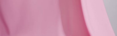 Gri panoramik çekimde izole edilmiş pembe yumuşak dalgalı kumaşın yakın görüntüsü