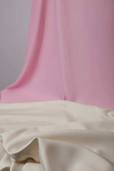selective focus of pink and white soft and wavy fabric isolated on grey