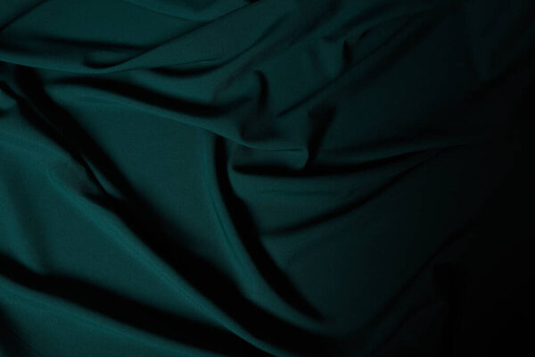 close up view of dark emerald soft and wavy silk fabric