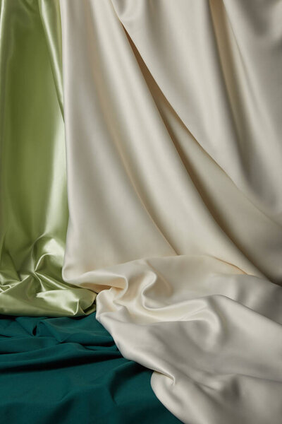 close up view of emerald, light green and white soft and wavy silk fabric