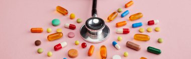 High angle view of stethoscope near bright colorful pills on pink background, panoramic shot clipart