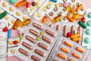 Top view of colorful capsules and pills on pink clipart