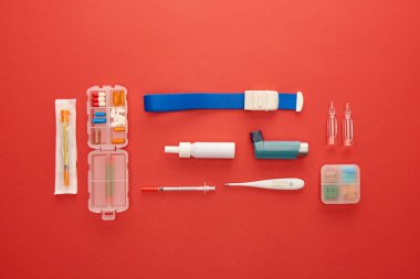 Flat lay with medicines and medical objects on red background clipart