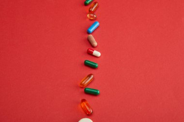 Kırmızı arkaplanda renkli hapların yüksek açılı görünümü