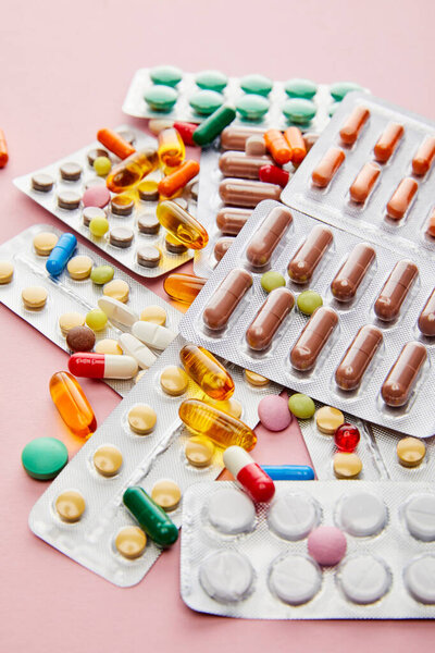 Selective focus of colorful medicines on pink background