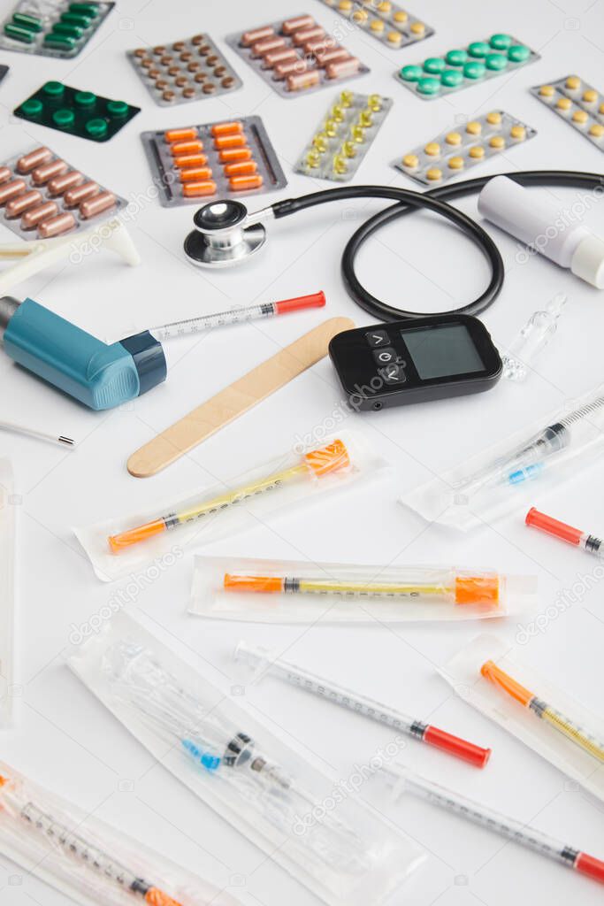 High angle view of colorful medicines, syringes and medical objects on white