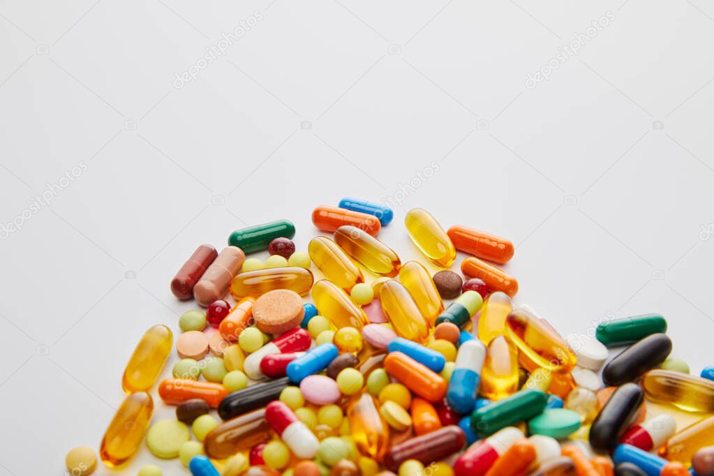High angle view of bright capsules and pills on white background