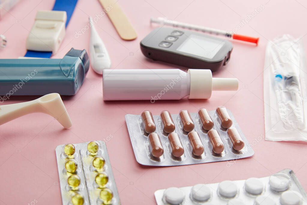 Selective focus of capsules, pills and medical objects on pink background