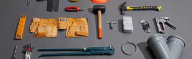 panoramic shot of industrial tools and tool belt on grey background clipart