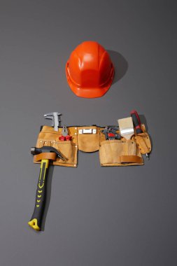 yüksek açı görünümlü miğfer, çekiç, fırça, pense, kalibreler, açı anahtarları ve gri arkaplanda tornavida.