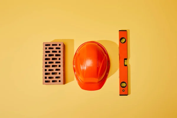 Vista Superior Ladrillo Casco Naranja Nivel Espíritu Sobre Fondo Amarillo — Foto de Stock