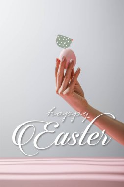 Kırpılmış tavuk yumurtası tutan kadının gri arka planda izole edilmiş görüntüsü. Mutlu Paskalya resimleriyle.