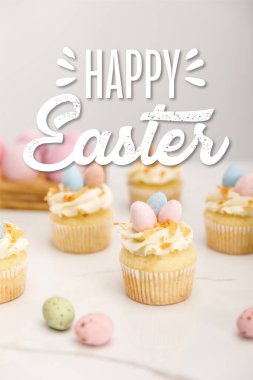 Paskalya çöreklerinin seçici odak noktası gri arka planda boyanmış bıldırcın yumurtaları ve mutlu Paskalya resimleriyle.