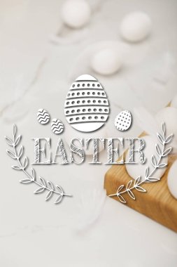 Yumurtaların seçici odak noktası ahşap yumurta tepsisi ve tüyler beyaz arka planda Paskalya resimli