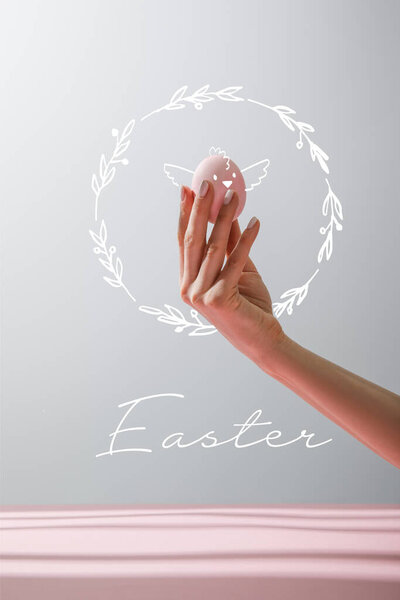 Cropped view of woman holding chicken egg isolated on grey background with Easter illustration