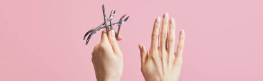Cropped view of woman holding cuticle pusher and nippers isolated on pink, panoramic shot clipart