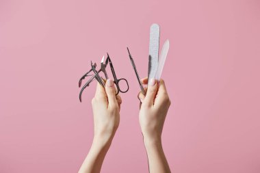Cropped view of woman holding manicure instruments isolated on pink clipart
