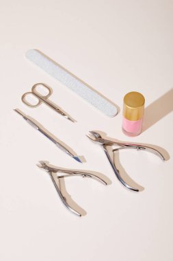High angle view of bottle of pink nail polish with manicure instruments on white background clipart