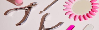 High angle view of samples of nail polish with manicure instruments on white, panoramic shot clipart