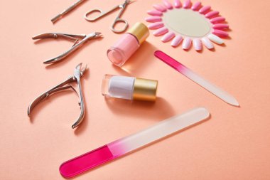 High angle view of bottles and samples of nail polish with manicure instruments on coral clipart