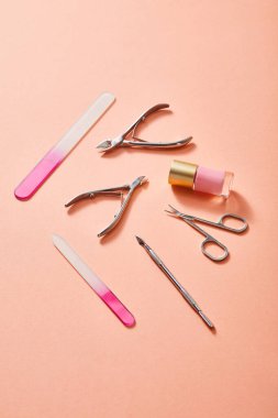 High angle view of bottle of pink nail polish and manicure instruments on coral background clipart