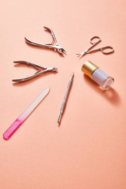 High angle view of bottle of white nail polish and manicure instruments on coral background clipart