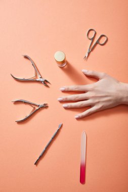Mercan üzerinde tırnak cilası ve manikür aletleriyle kesilmiş kadın eli.