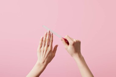 Pembe üzerine izole edilmiş tırnak törpüsü ile tırnaklarını törpüleyen kadın görüntüsü