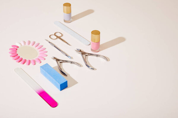 High angle view of bottles and samples of nail polish with manicure instruments on white background