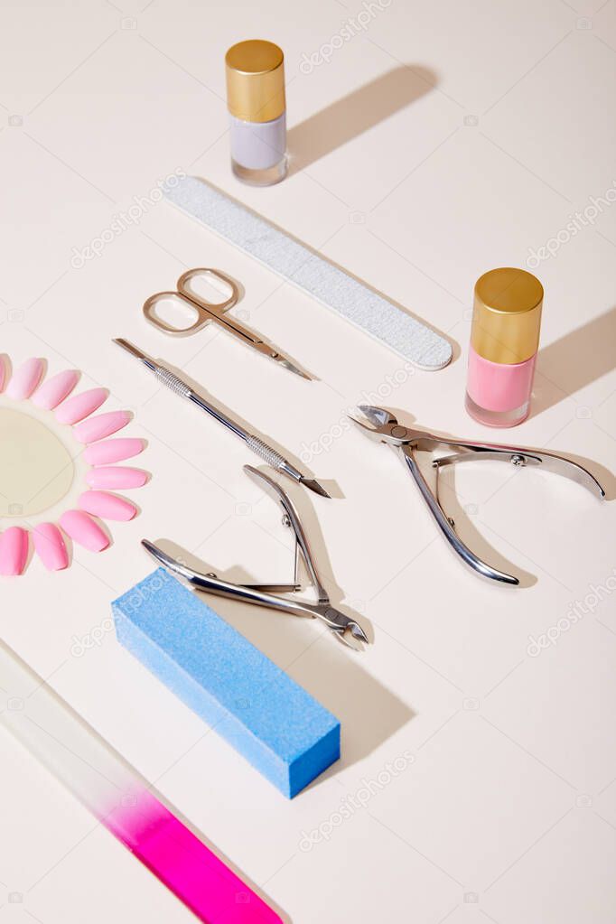 High angle view of bottles and samples of nail polish with manicure instruments on white 