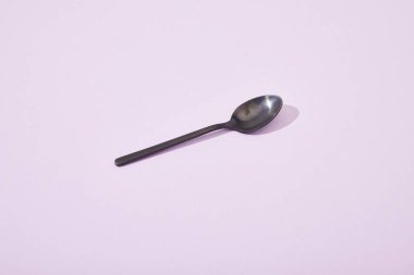 metal shiny black spoon on violet background clipart