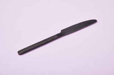 metal shiny black knife on violet background clipart