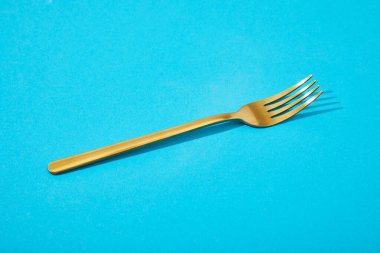 metal shiny golden fork on blue background clipart